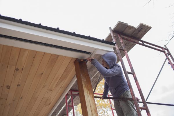 Mid adult woman painting varnish on wood outside house