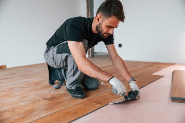 Using the rubber hammer. Man is installing new laminated wooden floor.